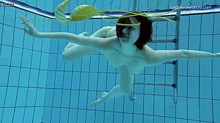 Russian redhead babe Lada bathes naked in the pool. Underwater shots reveal her little tits and sexy body.