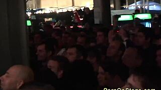 Blonde lesbians perform sex show with dildos on public stage.