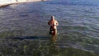 Milf plays with her big tits on the public beach