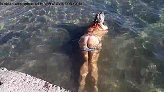 Milf plays with her big tits on the public beach