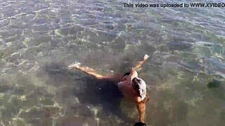 Milf plays with her big tits on the public beach