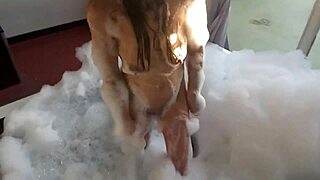 Spying on a brunette bathing, a guy in feminine clothing enters and they engage in intimate activities with her pear-shaped ass