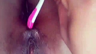 ebony performer inserts a brush into her anus for pleasure